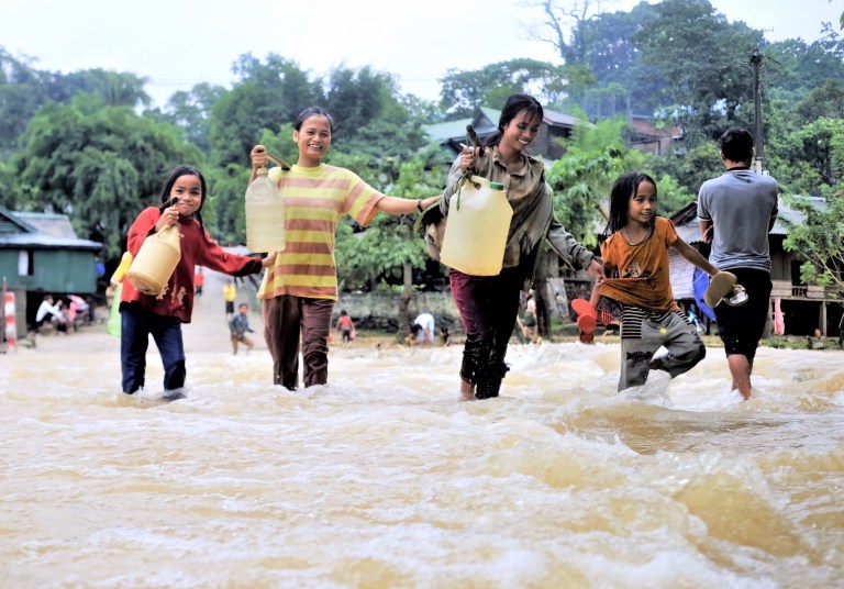 Girls collecting fresh water during floods. Cover image for blog post on gender-responsive climate finance.